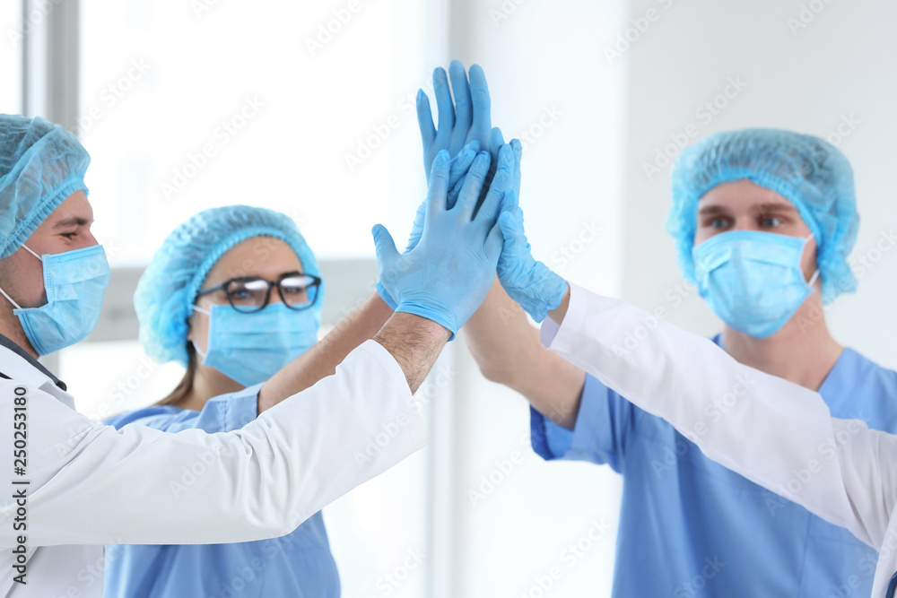 Fototapeta premium Team of doctors giving high five in clinic