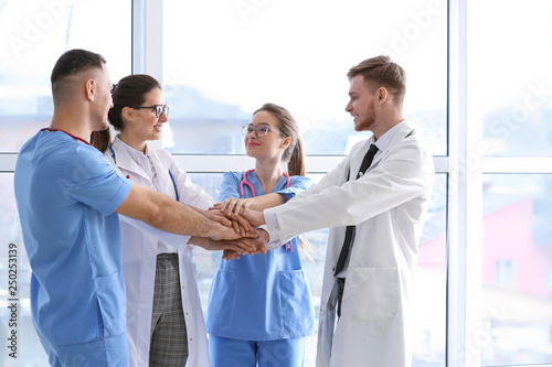 Team of doctors putting hands together in clinic