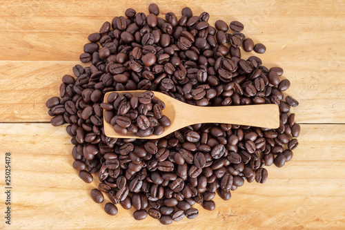 coffee beans and ground coffee in spoon on textured wood, close up, top-view.