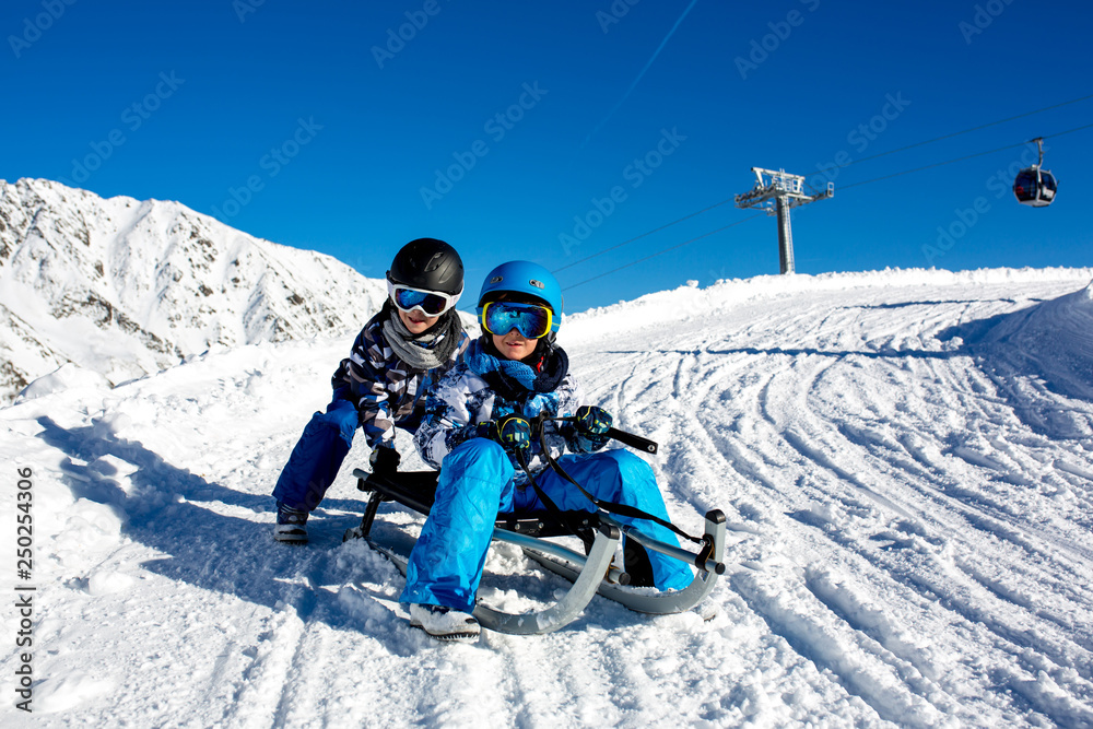 Happy people, children and adults, sliding on a sunny day in Tyrol mountains Happy people, children and adults, sliding on a sunny day in Tyrol mountains