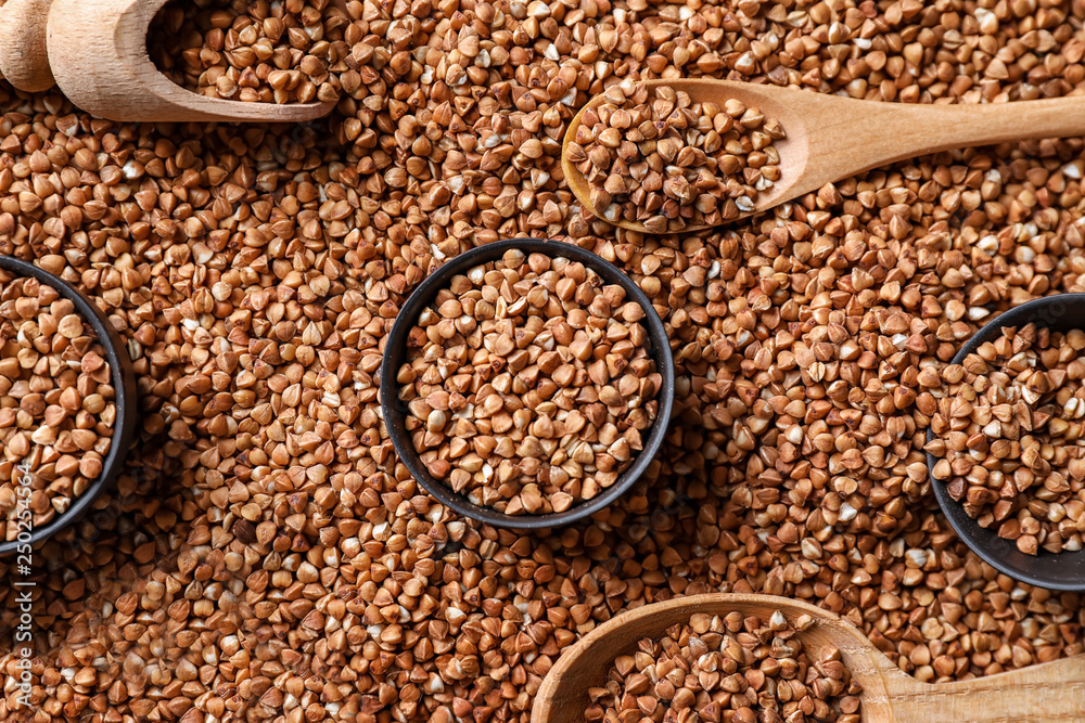 Obraz premium Bowls, spoons and scoop on raw buckwheat