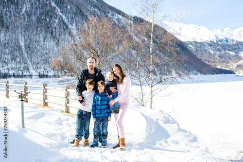 Family, enjoying winter view of snowy mountains and frozen lake © Tomsickova