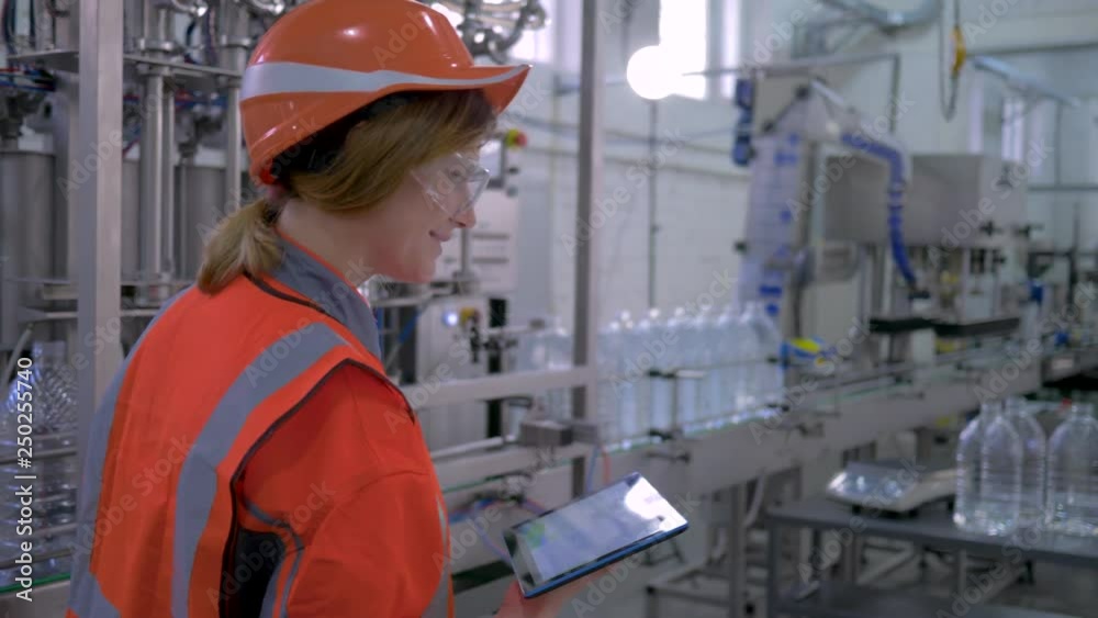 heavy female work, Factory specialist girl into hard hat uses computer tablet for revision and controls hardware operation in plant