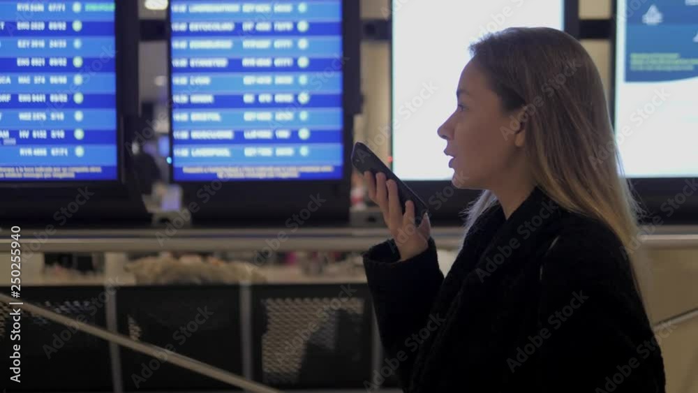 Travel woman using smartphone audio message voice recognition airport. Young caucasian traveler checking boarding time with mobile phone app in terminal or train station. Business woman businesswoman Travel woman using smartphone audio message voice recognition airport. Young caucasian traveler checking boarding time with mobile phone app in terminal or train station. Business woman businesswoman