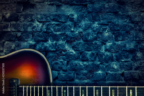 Old vintage jazz guitar on a brick wall background. Copy space. Background for concerts, festivals, music schools. Art,