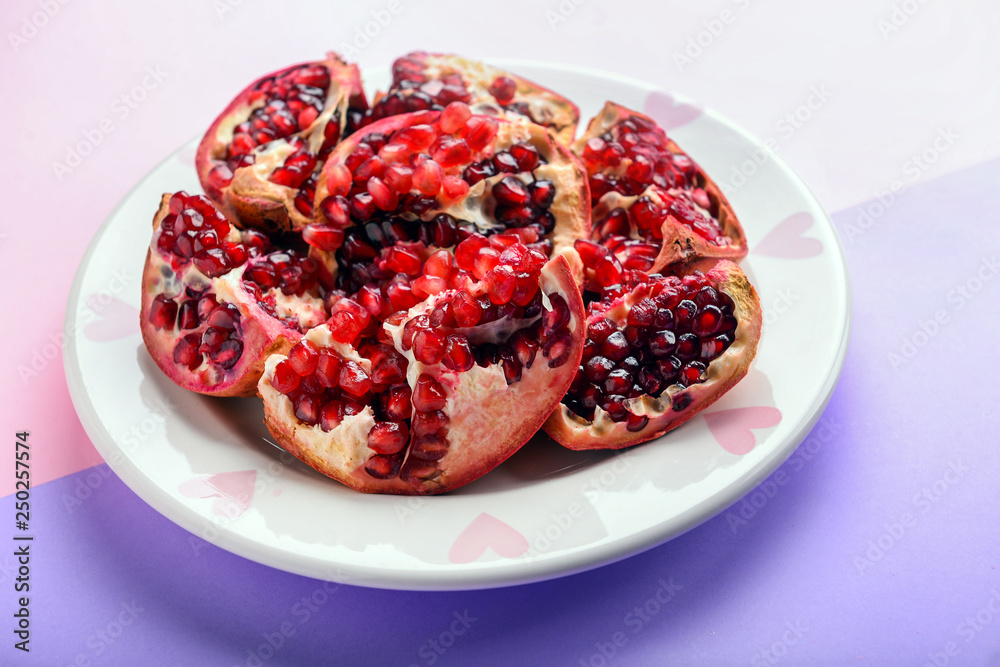 Plate with ripe pomegranates on color background Plate with ripe pomegranates on color background