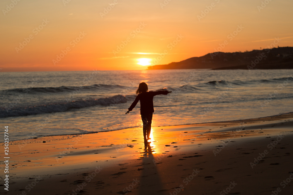 Happy child running on the beach during sunset, Praia da Luz, Algarve, Portugal