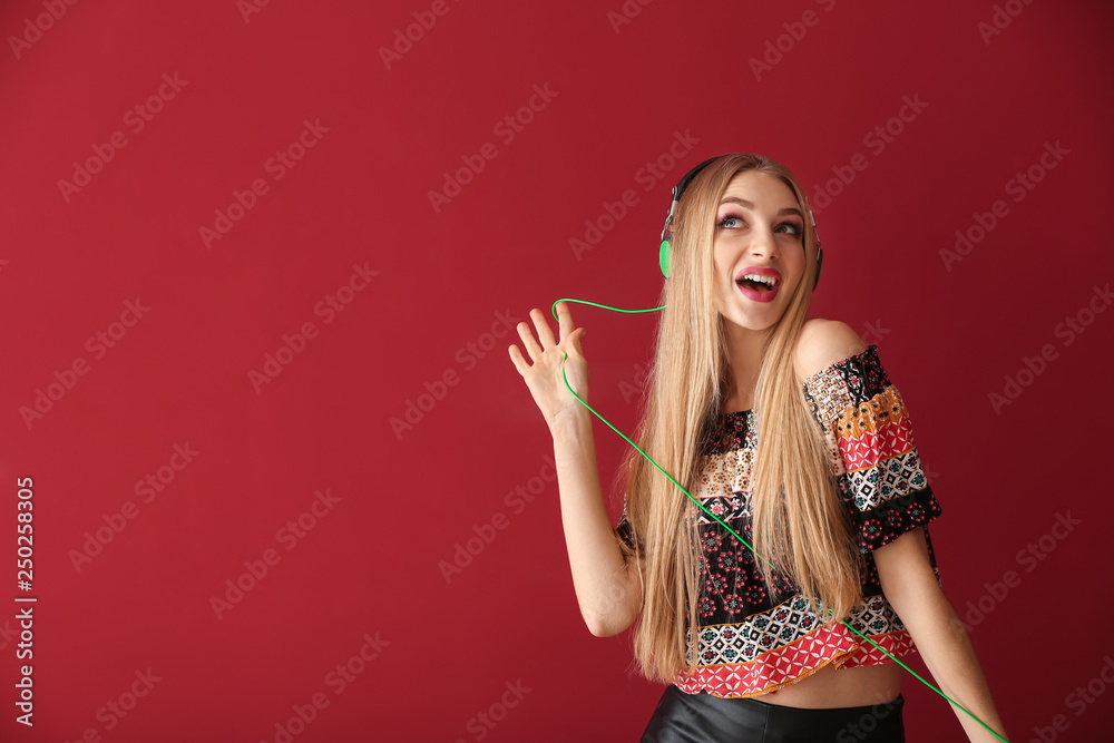 Obraz premium Beautiful young woman listening to music on color background