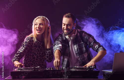 Male and female DJs playing music in club