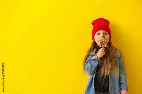 Stylish little girl with lollipop on color background © Pixel-Shot
