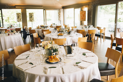 Wedding dinner table setting. Brown chairs stand at the round tables ready for festive dinner