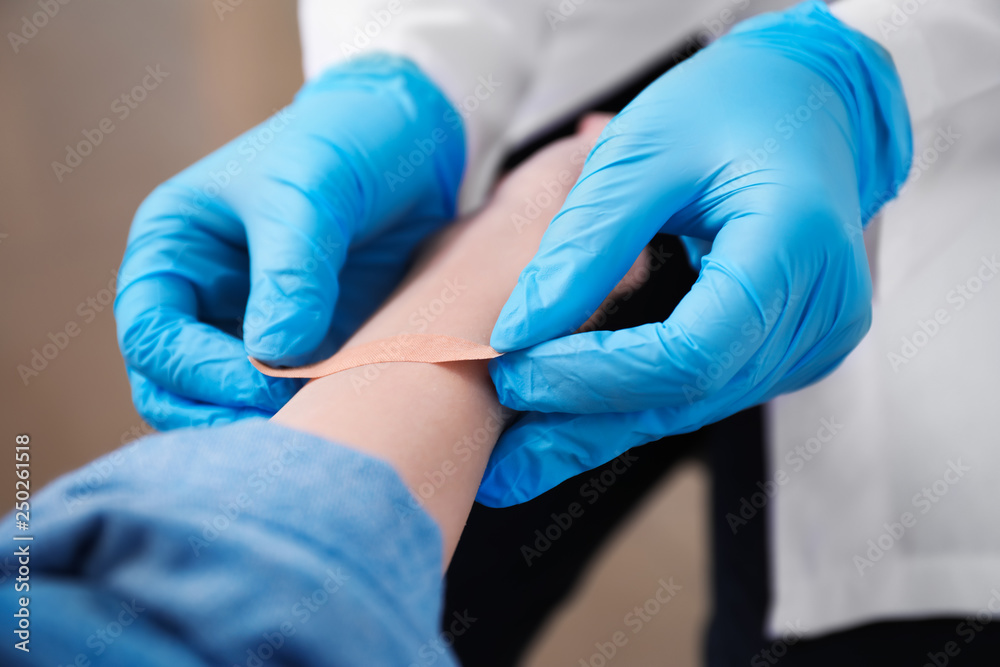 Doctor applying plaster onto hand of young woman, closeup Doctor applying plaster onto hand of young woman, closeup