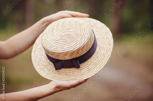 Hands with boater straw hat outdoors, french style fashion