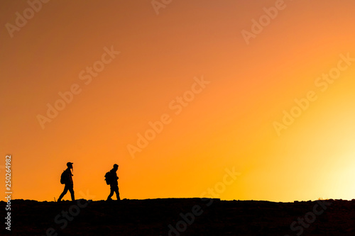 People silhouettes walking over mountain