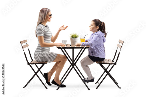 Young woman sitting at a table with coffee and talking to a little girl