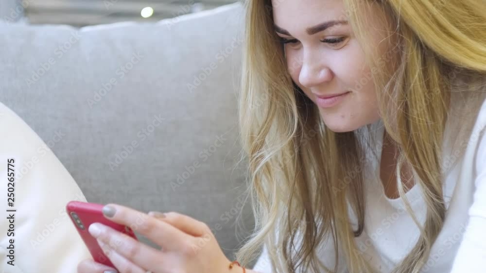 Beautiful young blonde is holding a phone in her hands, chatting, surfing the Internet and smiling Beautiful young blonde is holding a phone in her hands, chatting, surfing the Internet and smiling
