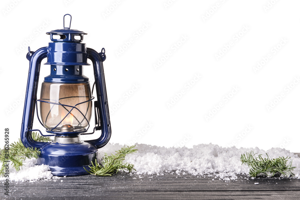 Lantern with snow and fir tree branches on wooden table against white background