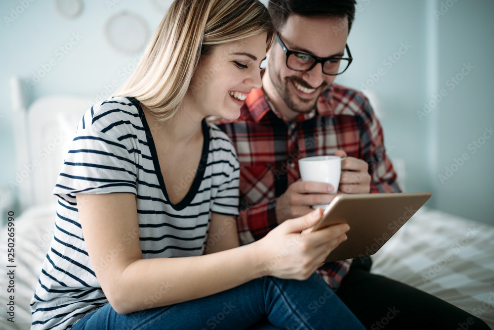 Young happy couple using tablet in bedroom Young happy couple using tablet in bedroom