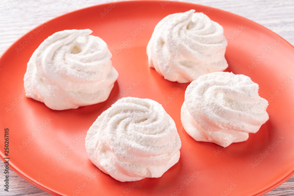 Homemade white marshmallow on an orange plate on an old wooden table in the kitchen. Homemade white marshmallow on an orange plate on an old wooden table in the kitchen.