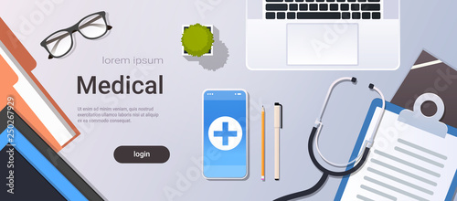 hospital worker table online mobile app top angle view doctor workplace desktop with laptop smartphone stethoscope and clipboard office stuff copy space horizontal
