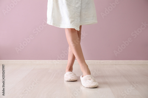 Young woman in slippers against color wall