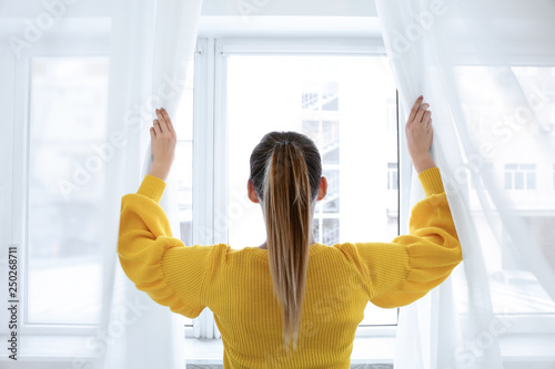Free Download Young woman opening curtains in morning - GFXLoad
