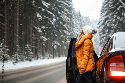 Young woman near car at winter resort