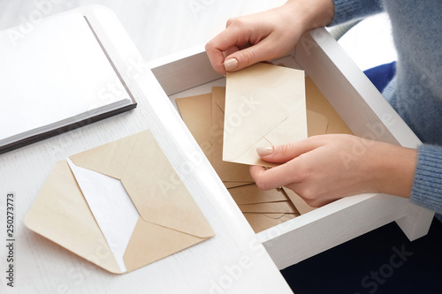 Young woman taking envelope from table drawer