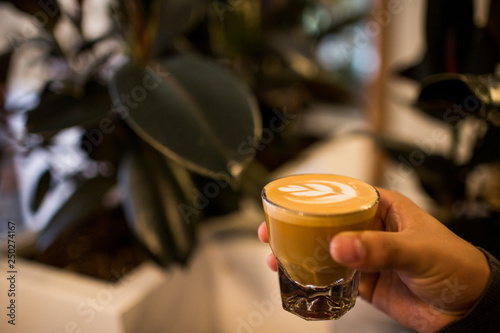 Brown hand holding cortado coffee latte art photo