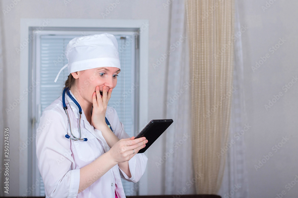 Female doctor or nurse looks at the tablet and is very shocked. The emotion of wonder and surprise. Female doctor or nurse looks at the tablet and is very shocked. The emotion of wonder and surprise.
