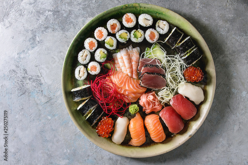 Sushi Set nigiri sashimi and sushi rolls in ceramic serving plate with salad over grey concrete background. Flat lay, space. Japan menu