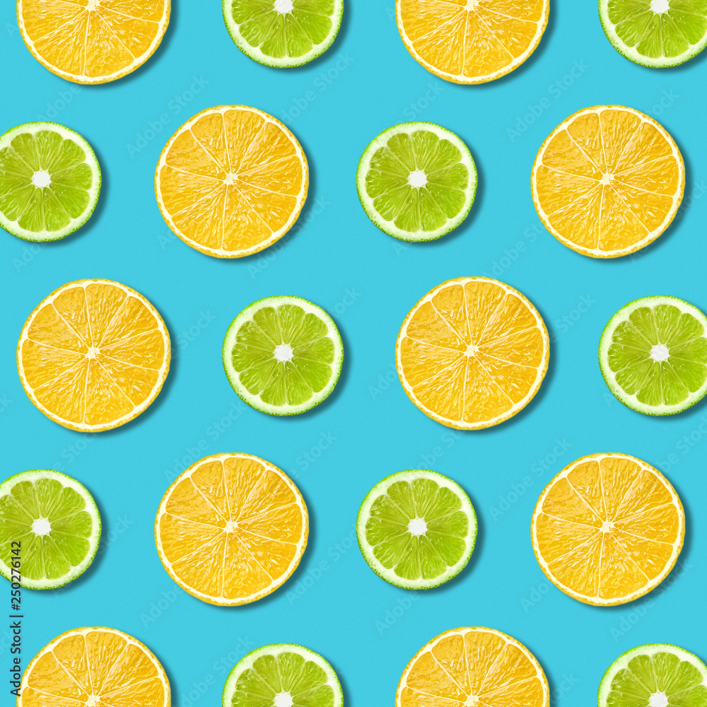 Vibrant lemon and green lime slices pattern on turquoise color background. Minimal flat lay top view food texture 