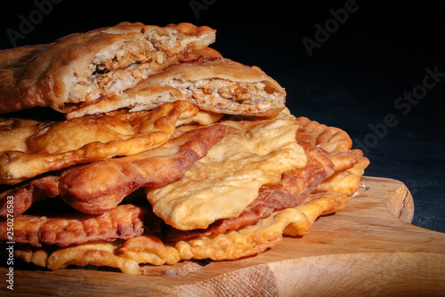 Hot homemade chebureki or chiburekki pies with minced meat and onion on a dark background, close-up