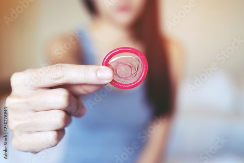 Condom ready to use in female hand, give condom safe sex concept on the bed Prevent infection and Contraceptives control the birth rate or safe prophylactic. World AIDS Day, Leave space for text. 