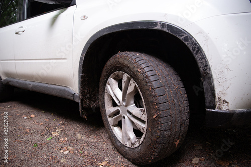 white suv car at forest trail wheel in dirt close up