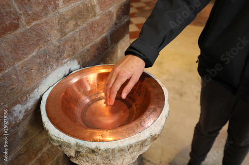Fotografie Faithful plunges his hand into the holy water