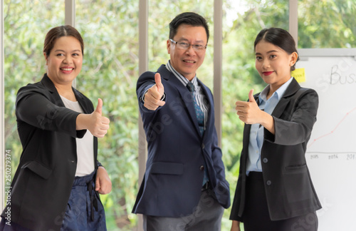 Blurred soft images of Businessmen are smiling and raising hands to make great symbols, because of business successful at workplace with green nature background to business concept.