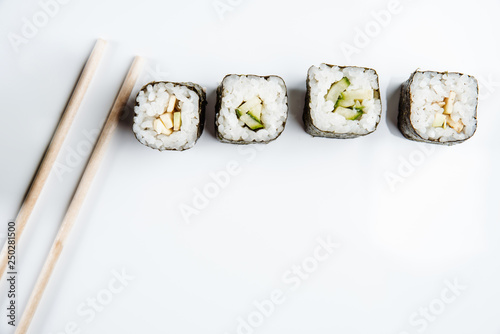 Two chopsticks, sushi and rolls on white background