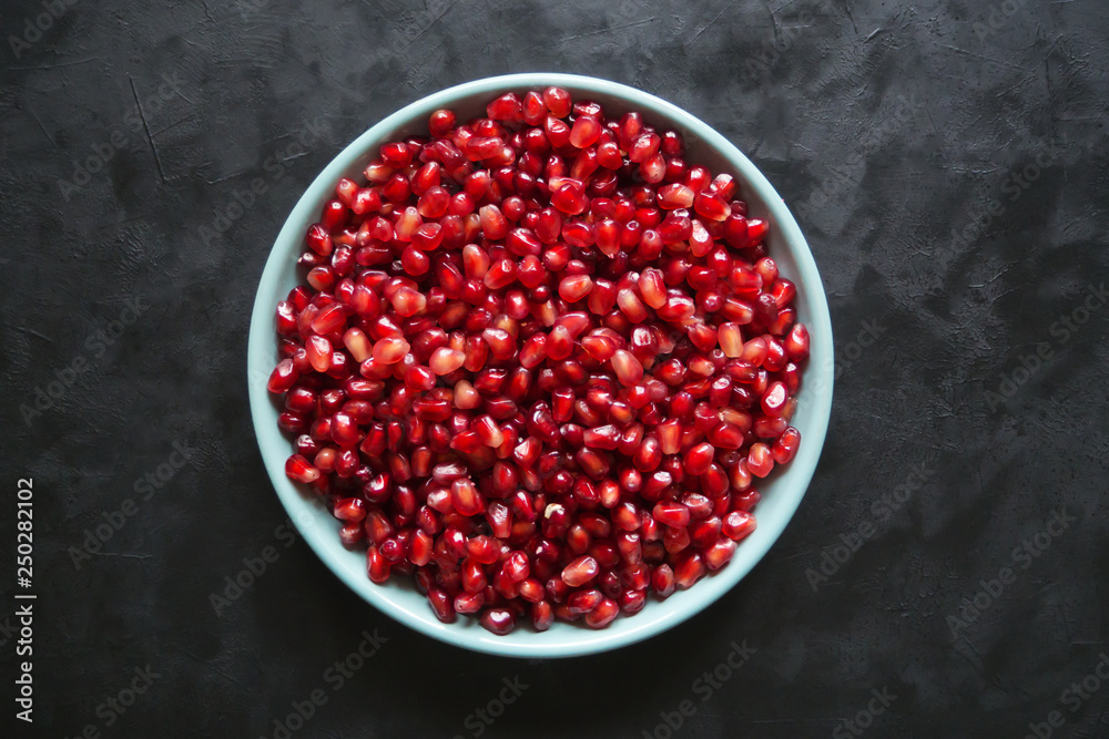 Pomegranate seeds on a plate on a black table. Pomegranate seeds on a plate on a black table.