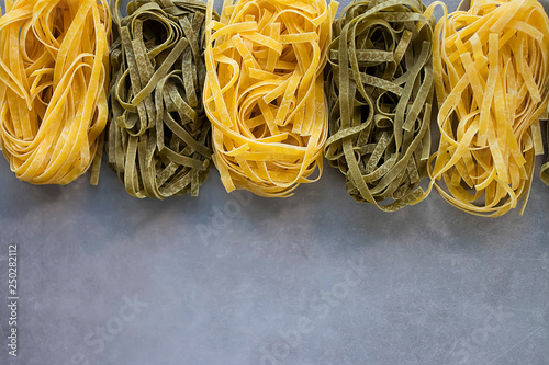 Two types of tagliatelle yellow and green. Egg and spinach noodles on a gray background. photo