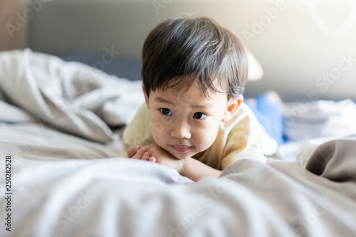 A kid is playing in the morning while watching TV in the bed in the bedroom.