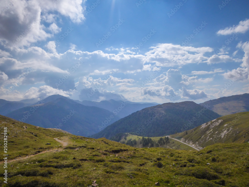 Mountain View on Carnic Alps, Austria. Endless chains of mountains, covered with clouds. Green mountain hills. Ble sky. Feeling of freedom, balance and relaxation