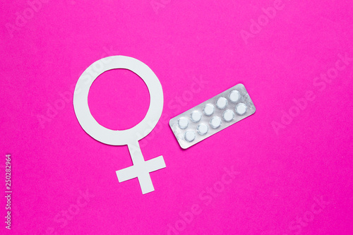 Women Health. Female gender symbol, pills on pink background. photo