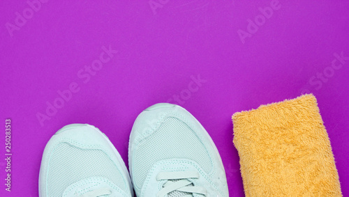 Training concept. Sport shoes, towel on a purple background. Copy space. Top view