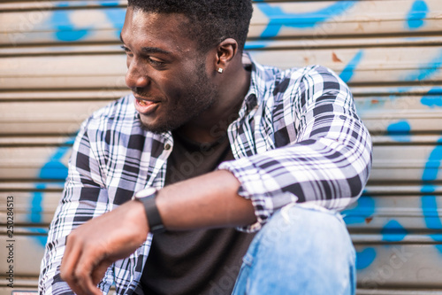 Black african european young man laughing - store door in background - urban lifestyle concept for young handsome boy photo