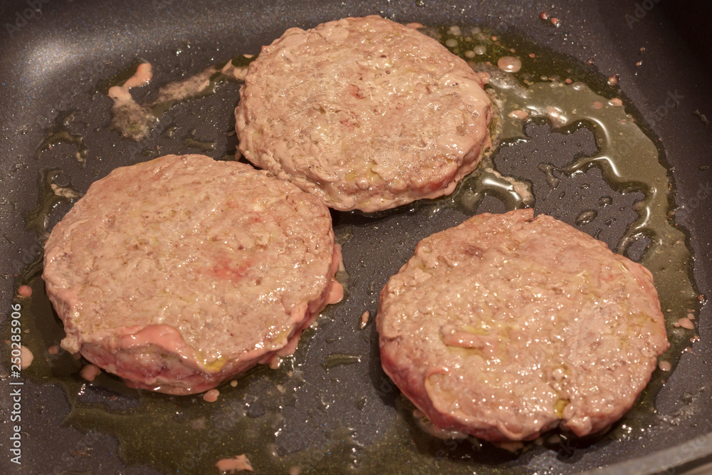 Greasy hamburger patty frying in a pan Greasy hamburger patty frying in a pan