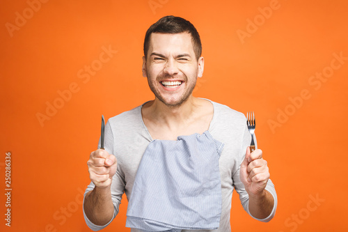 Fotografie, Obraz Young hungry crazy man holding a fork and a knife