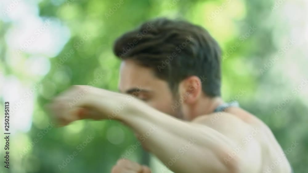 Male boxer training in park. Young man boxer training punch in air Male boxer training in park. Young man boxer training punch in air