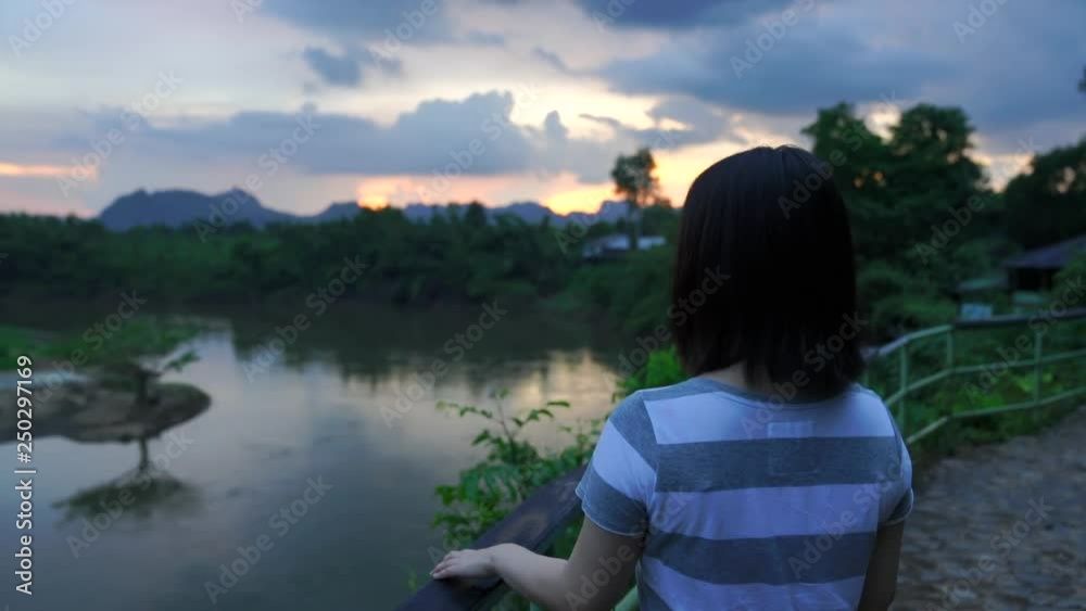 young japanese teen girl brunette tourist adult woman asian mature backpack looking the sky outdoors on a hike mountains viewpoint at River Kwai, Sai Yok National Park, Kanchanaburi, Thailand.