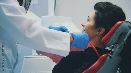 Dentist and patient. Young beautiful dentist repairing teeth of a beautiful young woman in the dentist's office. Dentist wearing surgical gloves white uniform and mask.